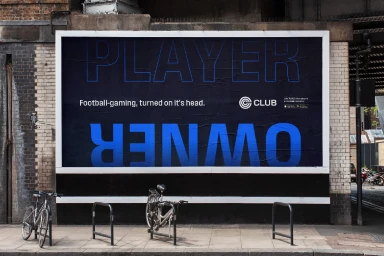 Outdoor billboard advertisement for Formation Games showing the words PLAYER and OWNER in blue on a black background mounted on a brick wall