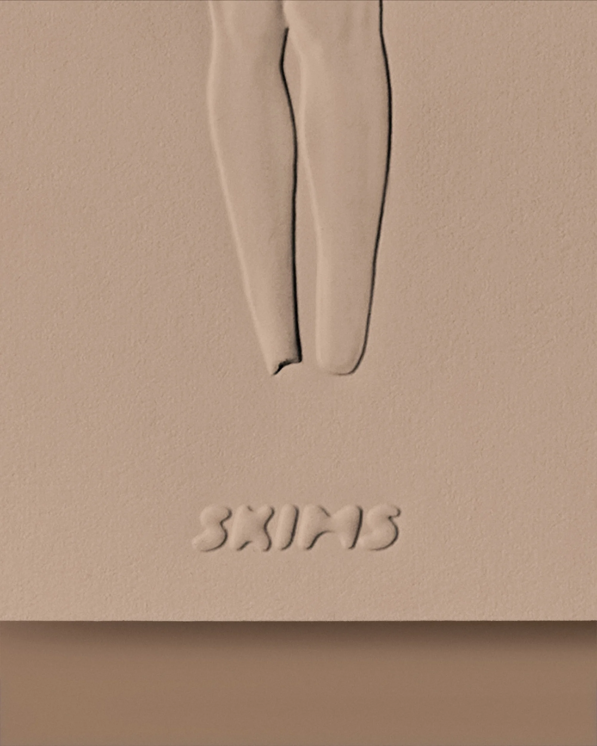 Close-up shot of a promotional studio image with embossed SKIMS brand lettering below sculpted legs, set against a neutral beige backdrop.
