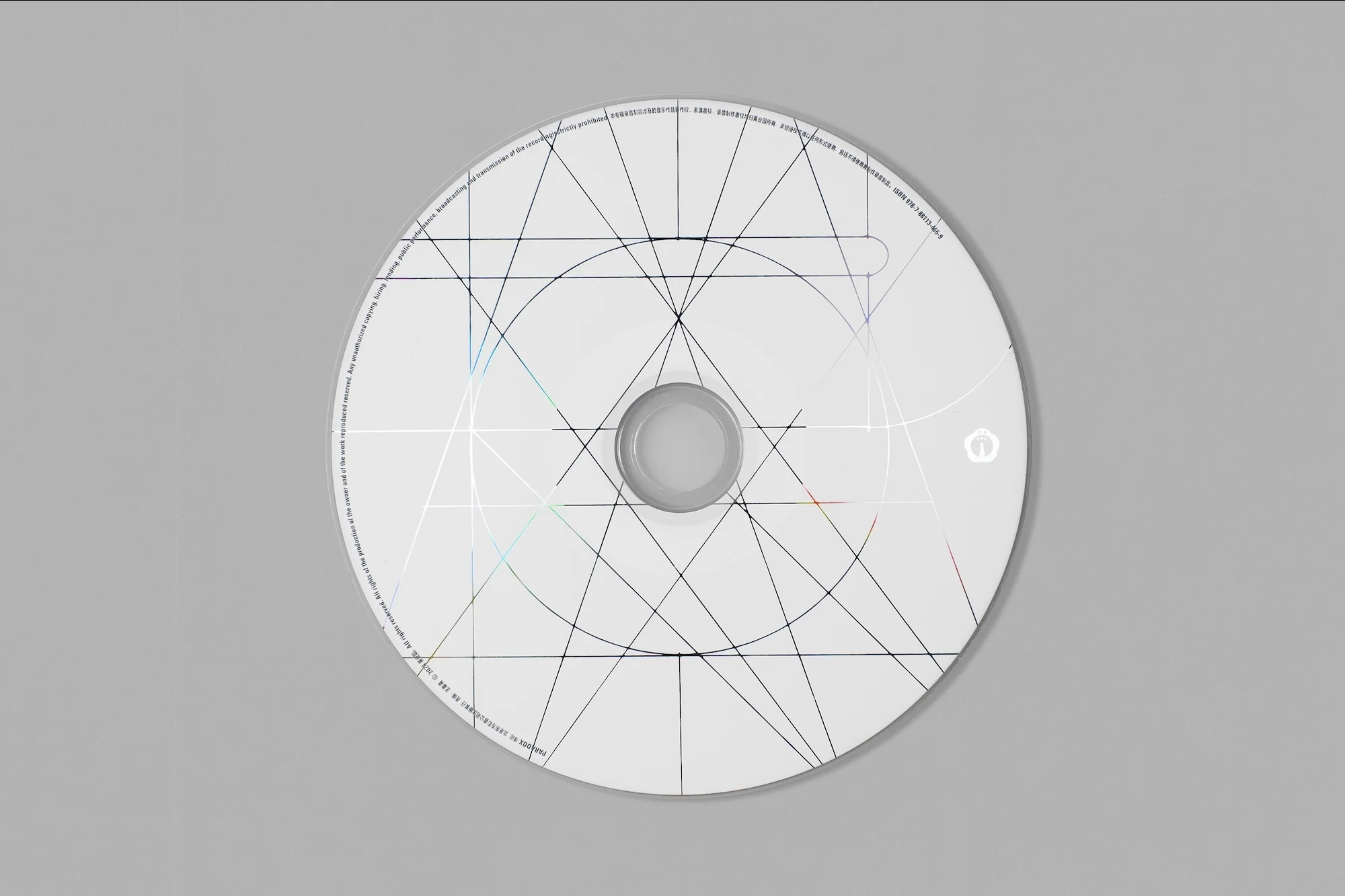 White compact disc featuring geometric line art patterns, photographed against a plain grey background in a well-lit, eye-level studio setting.