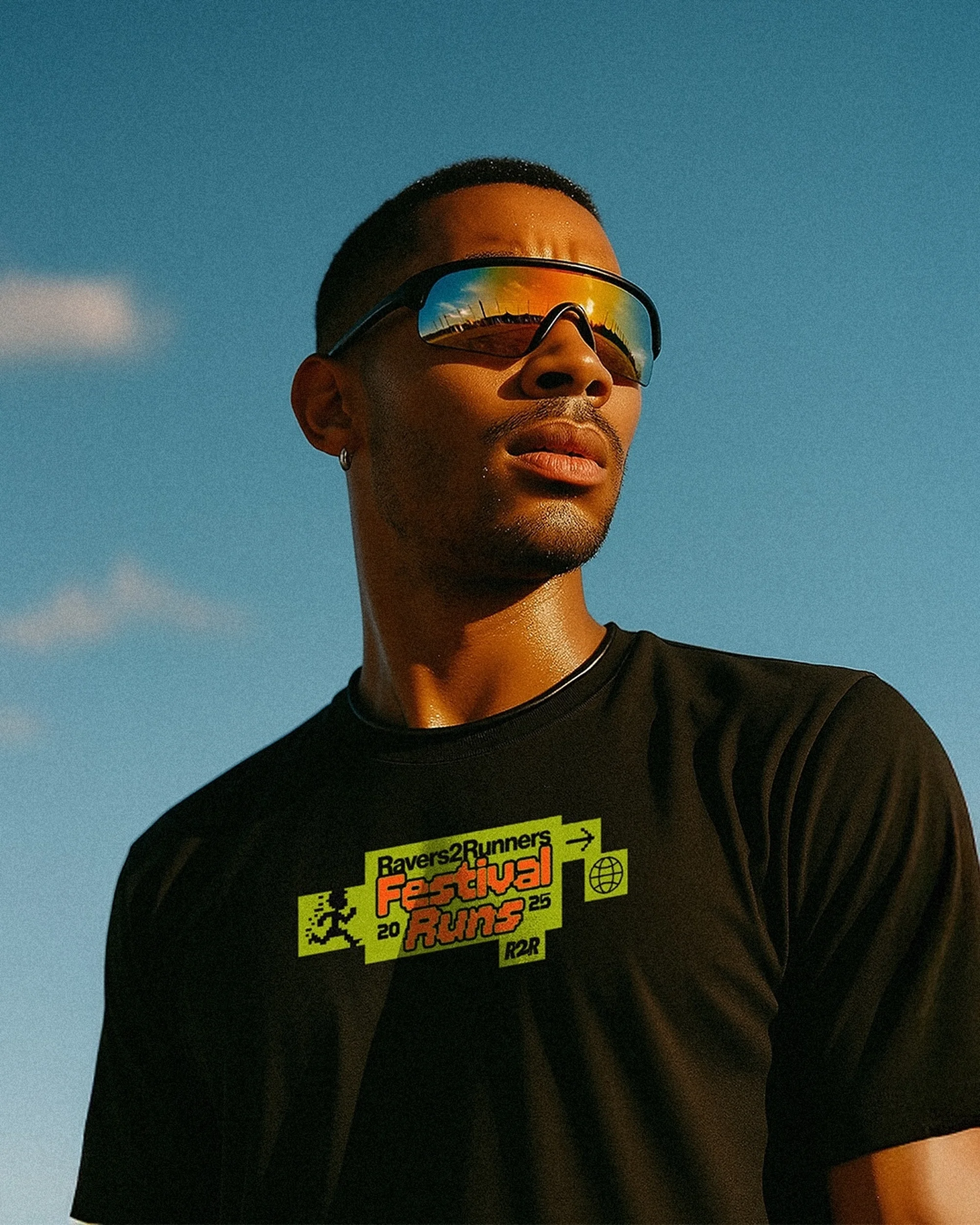 A portrait of a stylish adult male wearing reflective sunglasses against a blue sky, showcasing fashion and outdoor fitness.