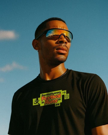 A portrait of a stylish adult male wearing reflective sunglasses against a blue sky, showcasing fashion and outdoor fitness.