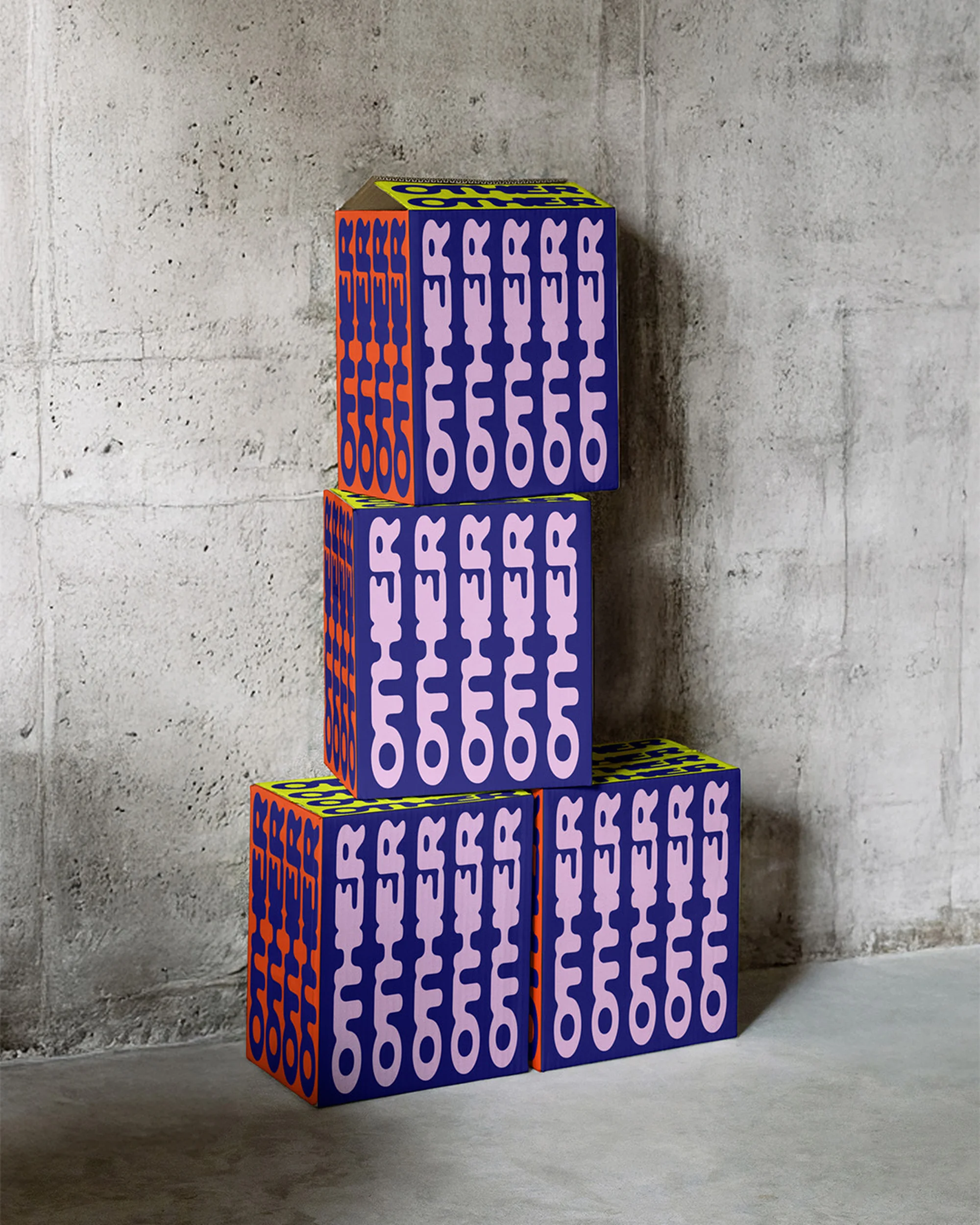 Three colorful cubes with abstract text stacked in front of a gray concrete wall, in a studio setting with balanced lighting.