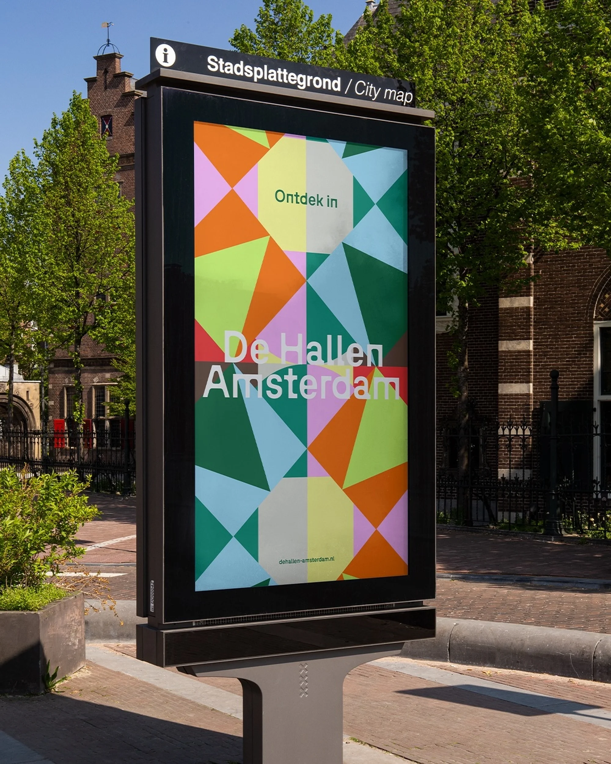 City map on an advertising display in Amsterdam features colorful geometric designs and text in Dutch and English in an outdoor setting.