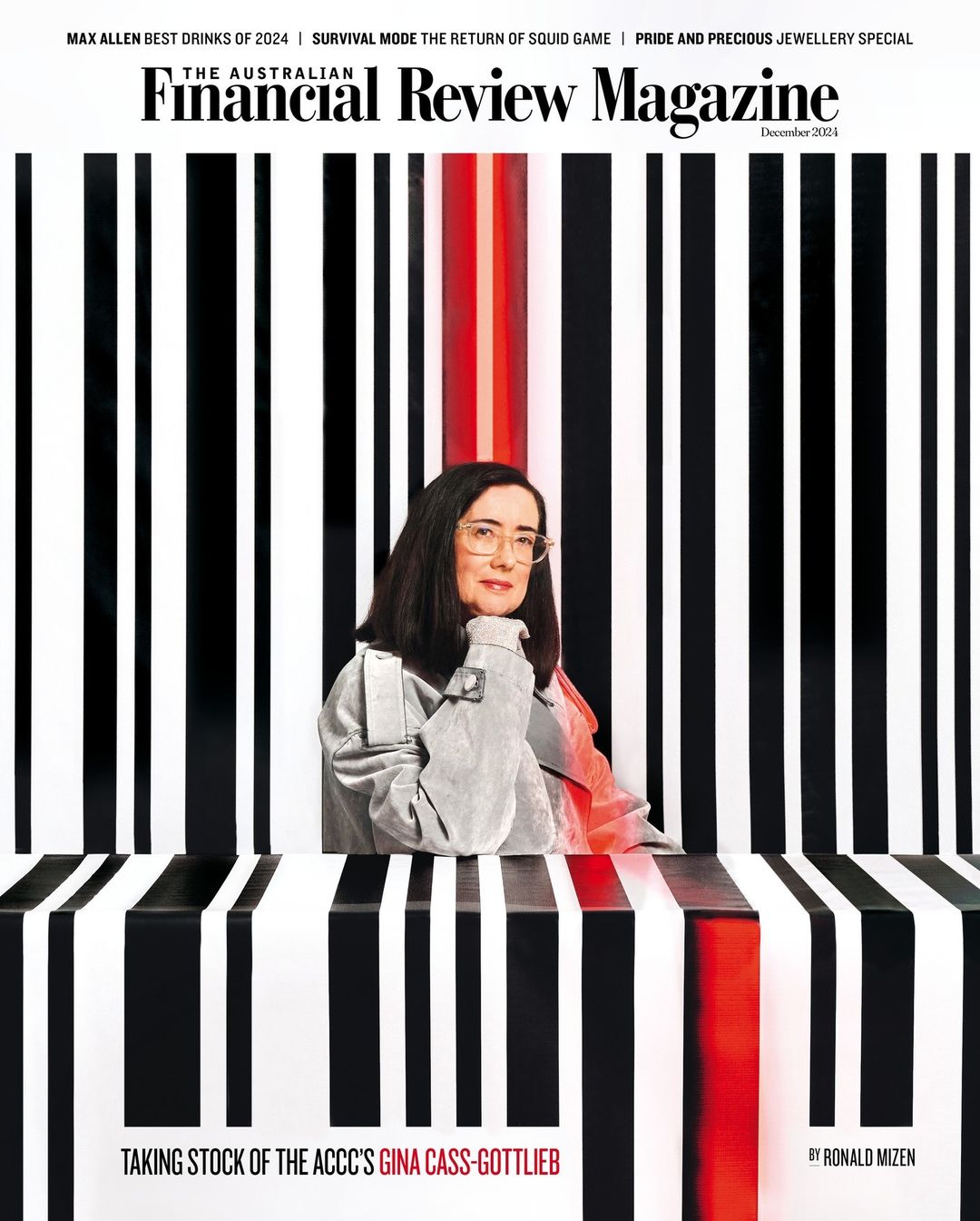 Magazine cover featuring a woman with glasses and a gray jacket, posed against a striped black, white, and red background.