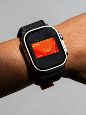 Close-up of a wrist wearing a smart watch displaying a digital card, set against a neutral grey background. Wrist watch has a black band.