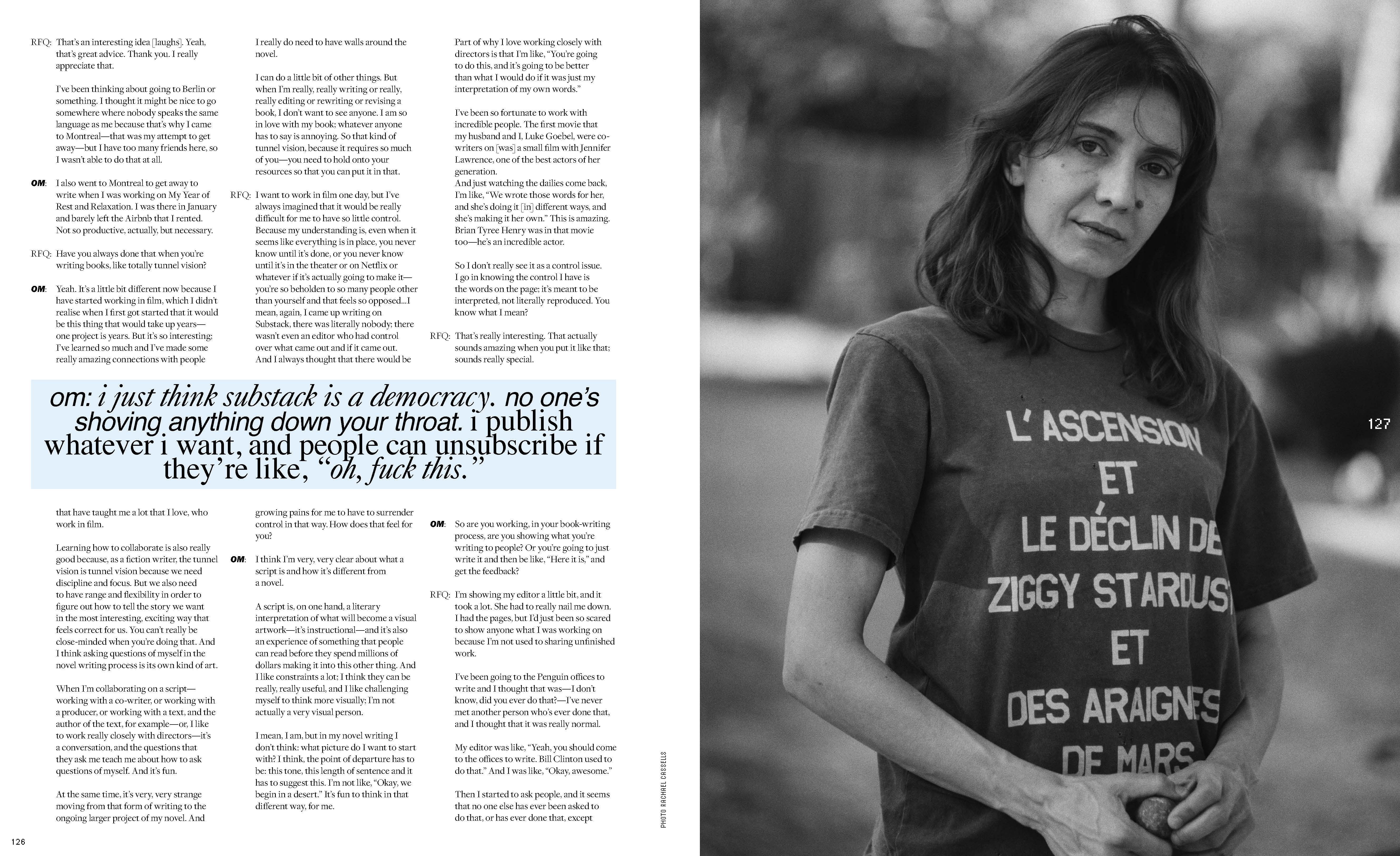 Black-and-white portrait of a woman in a t-shirt with French text, standing outdoors with a blurred background of trees and foliage.