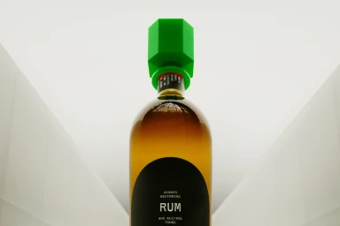 Bottle of rum with a bright green hexagonal cap set against a white architectural background