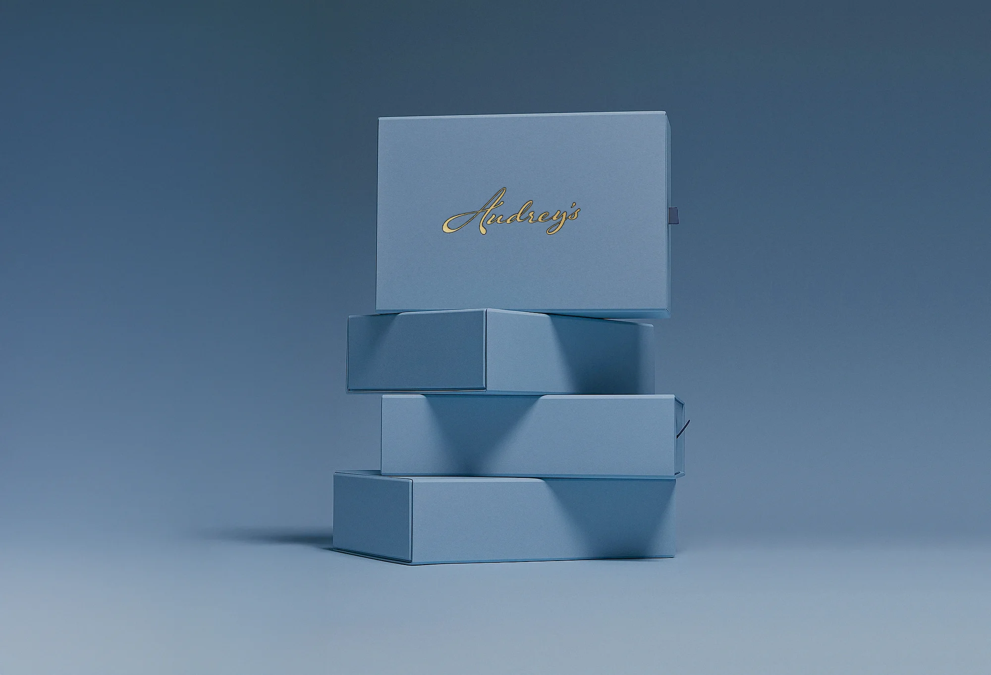Stack of light blue gift boxes with golden text logo on a matching blue background, simple product photography for e-commerce.