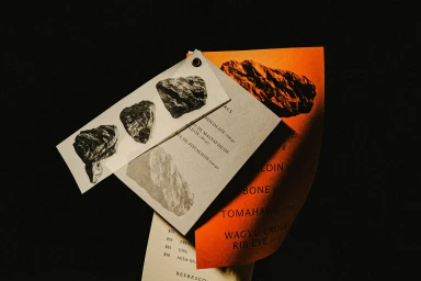 Printed menus and cards featuring black and white rock illustrations layered against a dark background