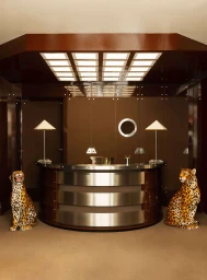 Curved reception desk with metal bands and two seated leopard statues in Hotel Chateau d'Eau lobby interior.