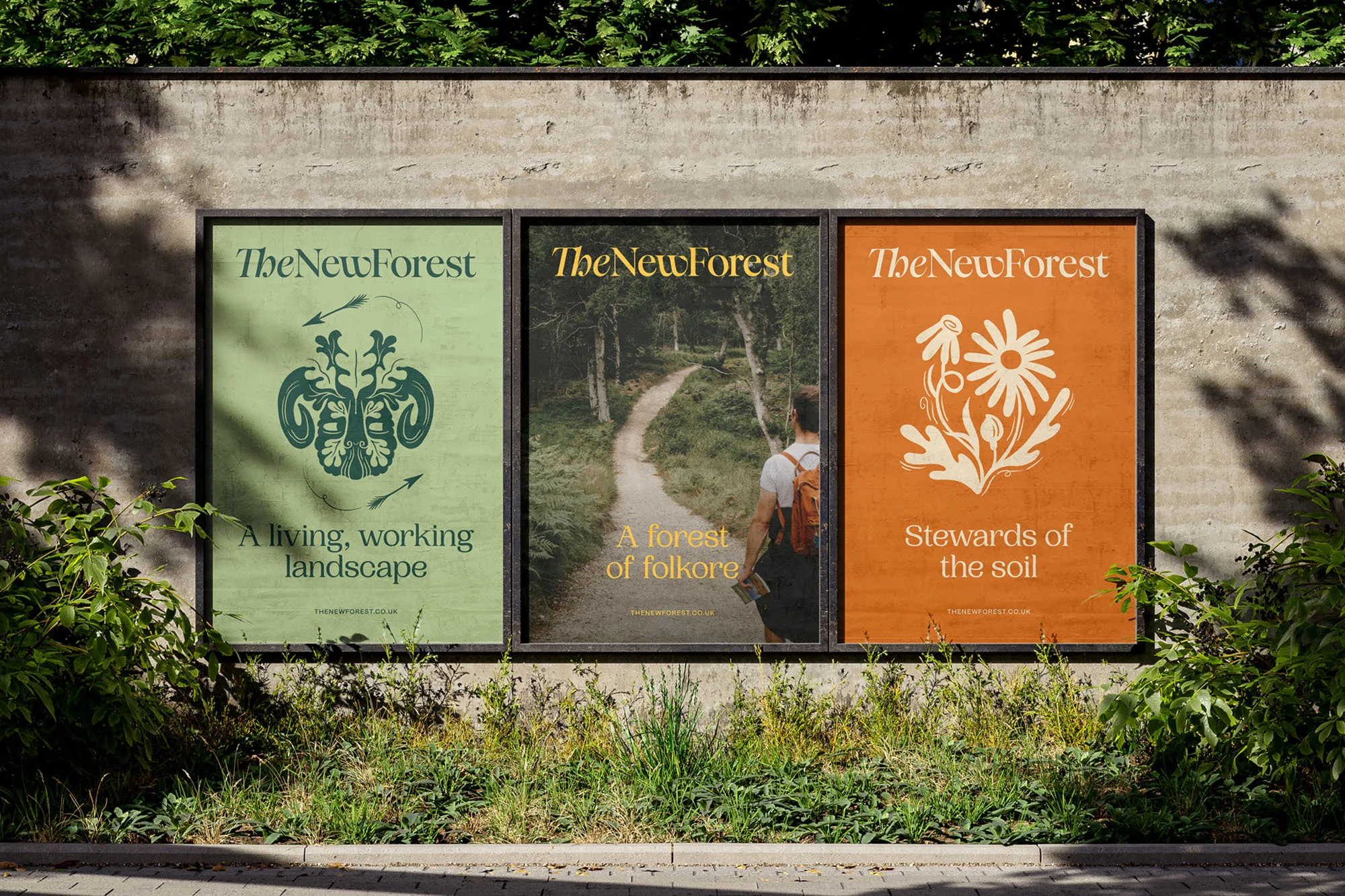 Three posters on a concrete wall, displaying landscape designs and the text 'The New Forest', surrounded by green foliage.