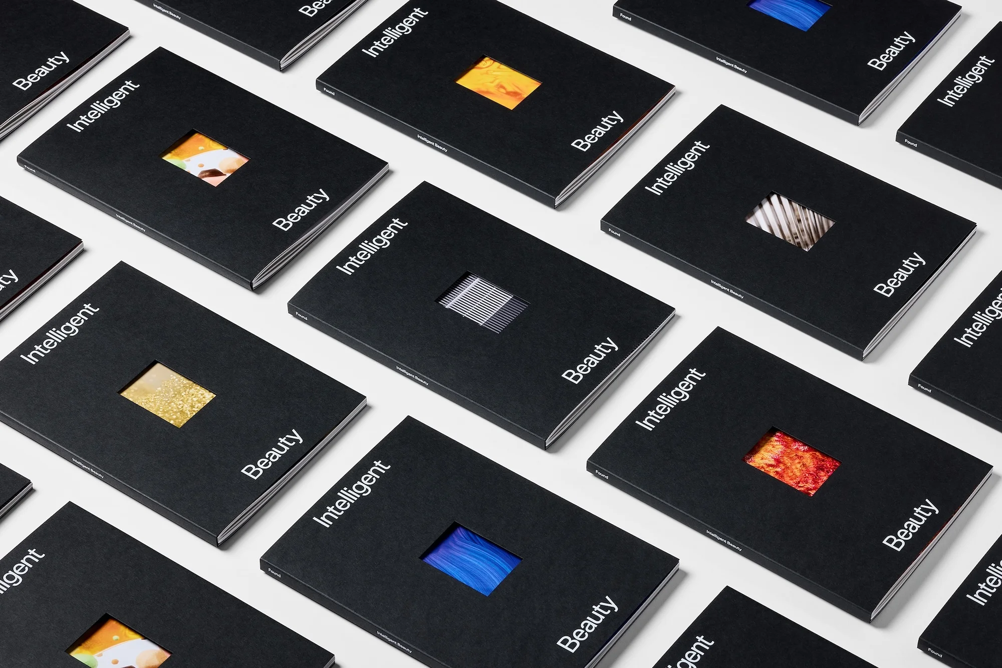Multiple black books with white Intelligent Beauty typography and small cutout windows arranged neatly on a white surface