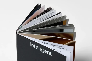 An open hardcover book titled Intelligent with fanned white and dark pages against a clean light background