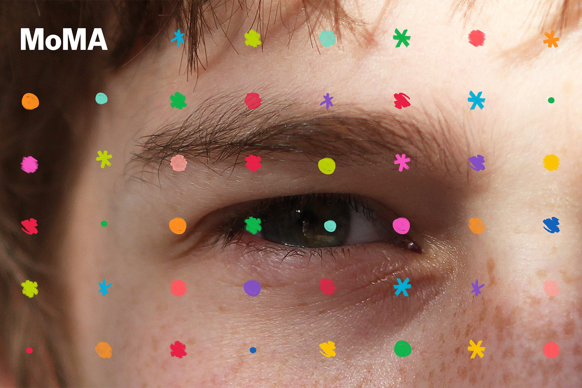 Macro shot of a human eye and eyebrow with colorful abstract dots and star shapes. Light skin tone and brown hair are visible.