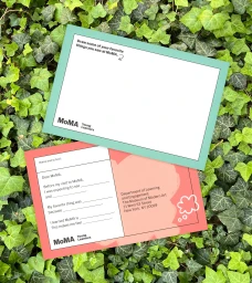 Two colorful activity cards for MoMA Young Learners resting on lush green ivy foliage.