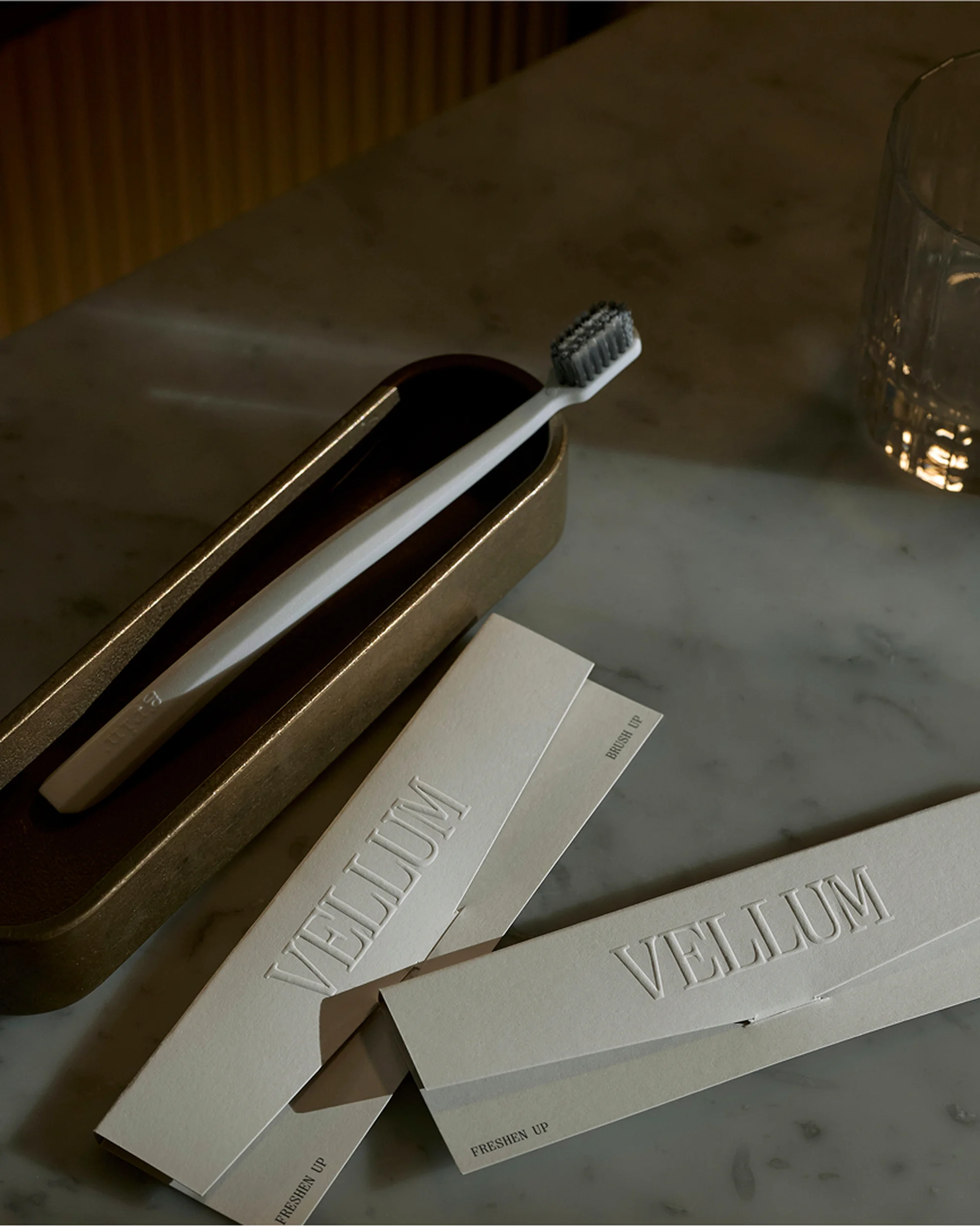 Elevated view of a toothbrush and 'Vellum' branded packaging on a marble surface, creating a clean and sophisticated dental product image.