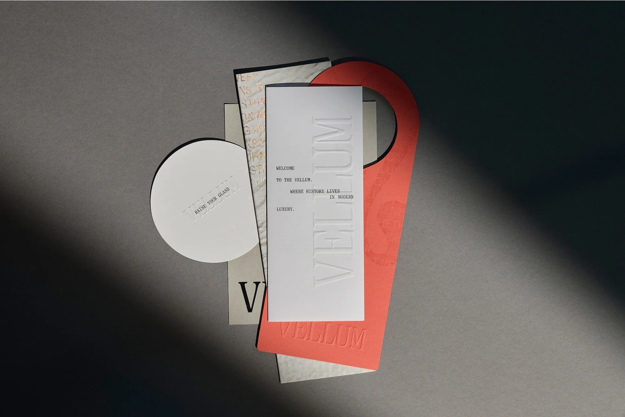 Arrangement of stationery items with a door hanger, cards, and paper circle against a grey background, captured with diffused light.
