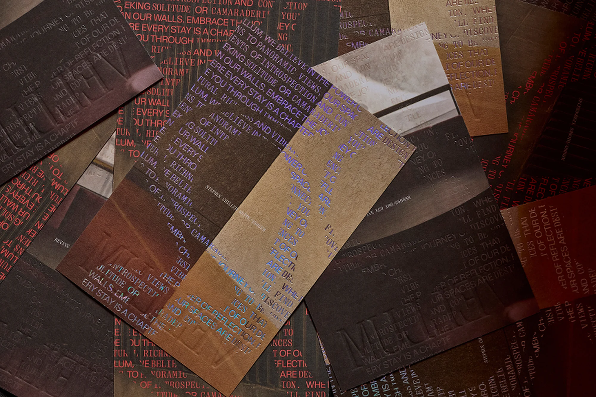 Scattered embossed paper cards with various texts in orange, purple and black create an abstract, textured design on a dark surface.