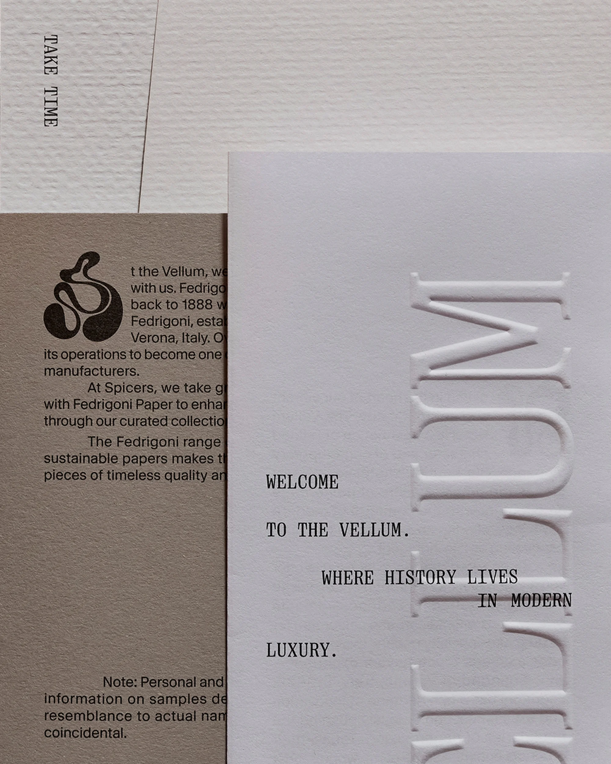 Close-up of paper samples featuring embossed and letterpress text on different paper textures and weights, with neutral tones.