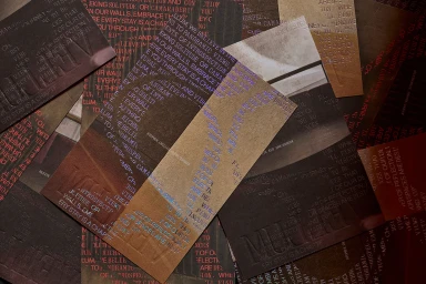 Close-up overhead arrangement of dark textured paper samples featuring embossed typography and foil stamping by Fedrigoni