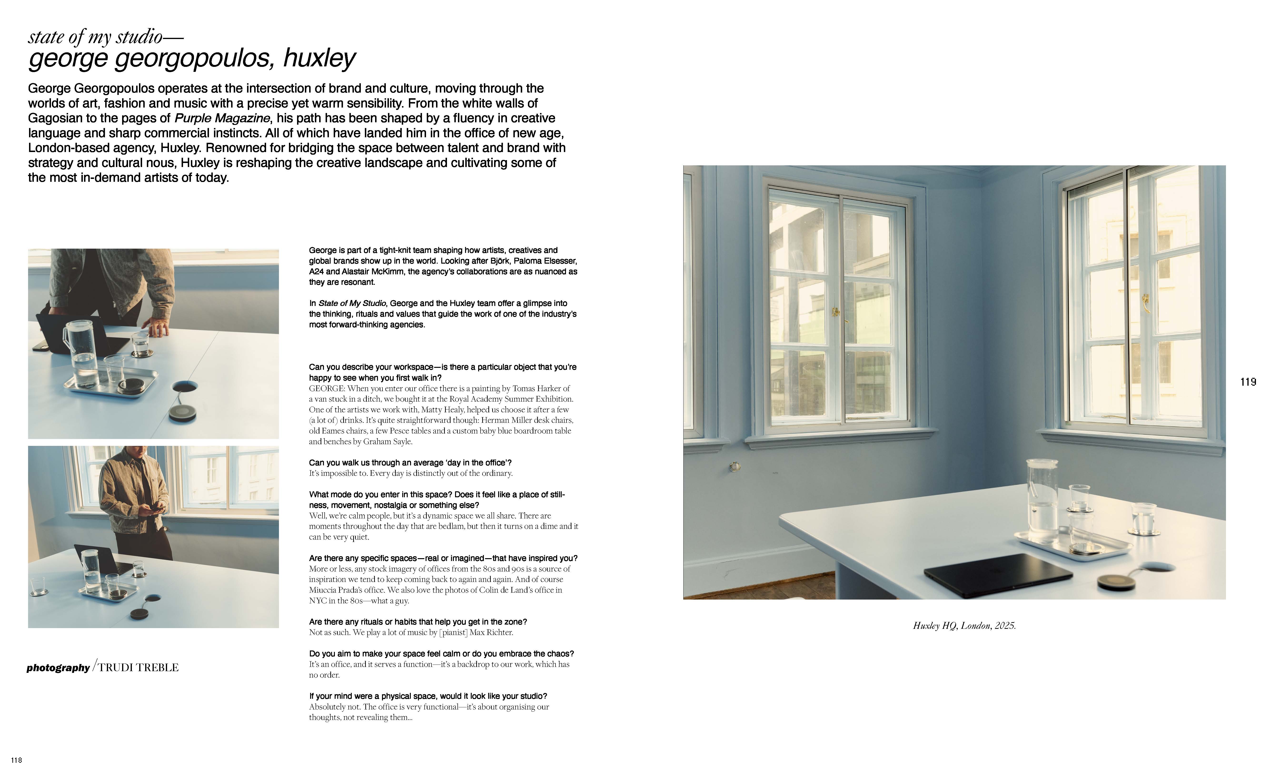 Bright architectural shot of a light blue room with windows and a table holding glasses, a laptop, and other objects in a serene setting.