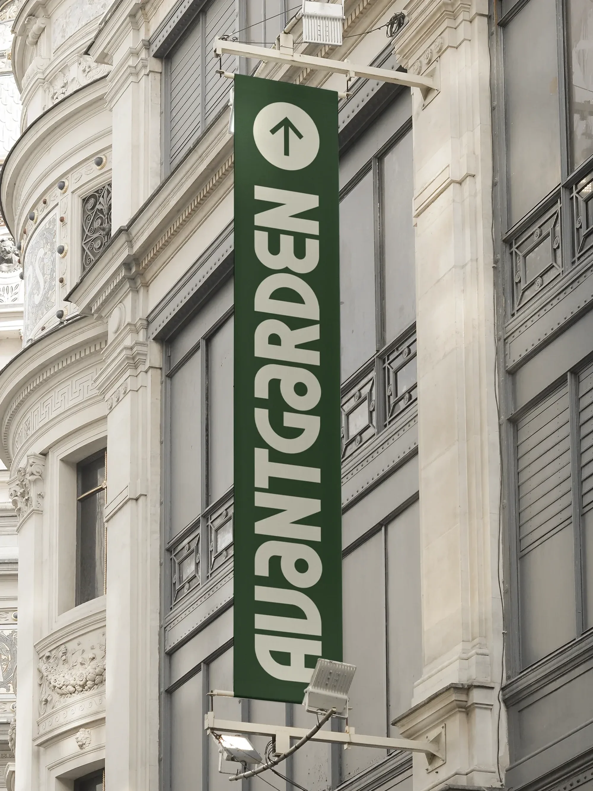 Exterior of a building with a green sign reading AVANTGARDEN with an arrow pointing up hanging outside.