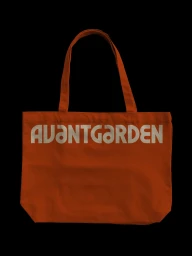 Rust orange canvas tote bag with bold cream typography branding against a solid black background.
