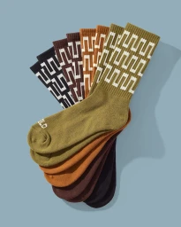 An arrangement of folded crew socks in olive, rust, brown, and black with a white geometric pattern against a blue background.