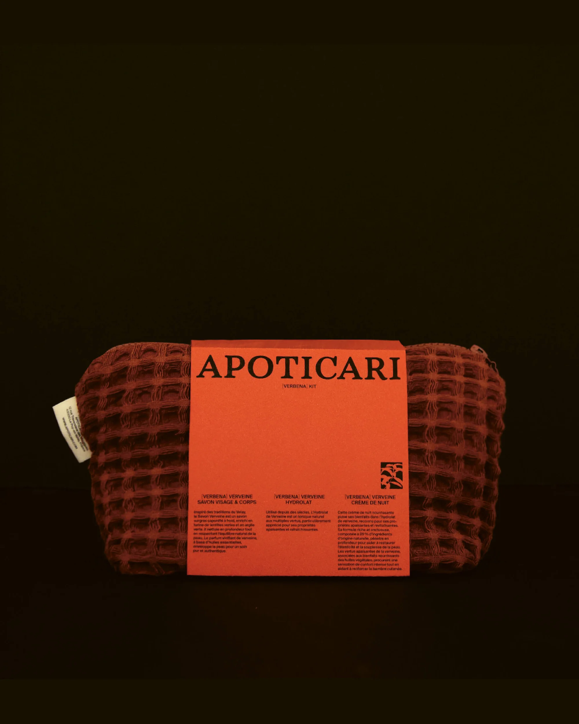 Apoticari product is displayed, a red patterned cloth with a red label, on a dark backdrop, in a beauty or personal care still life shot.