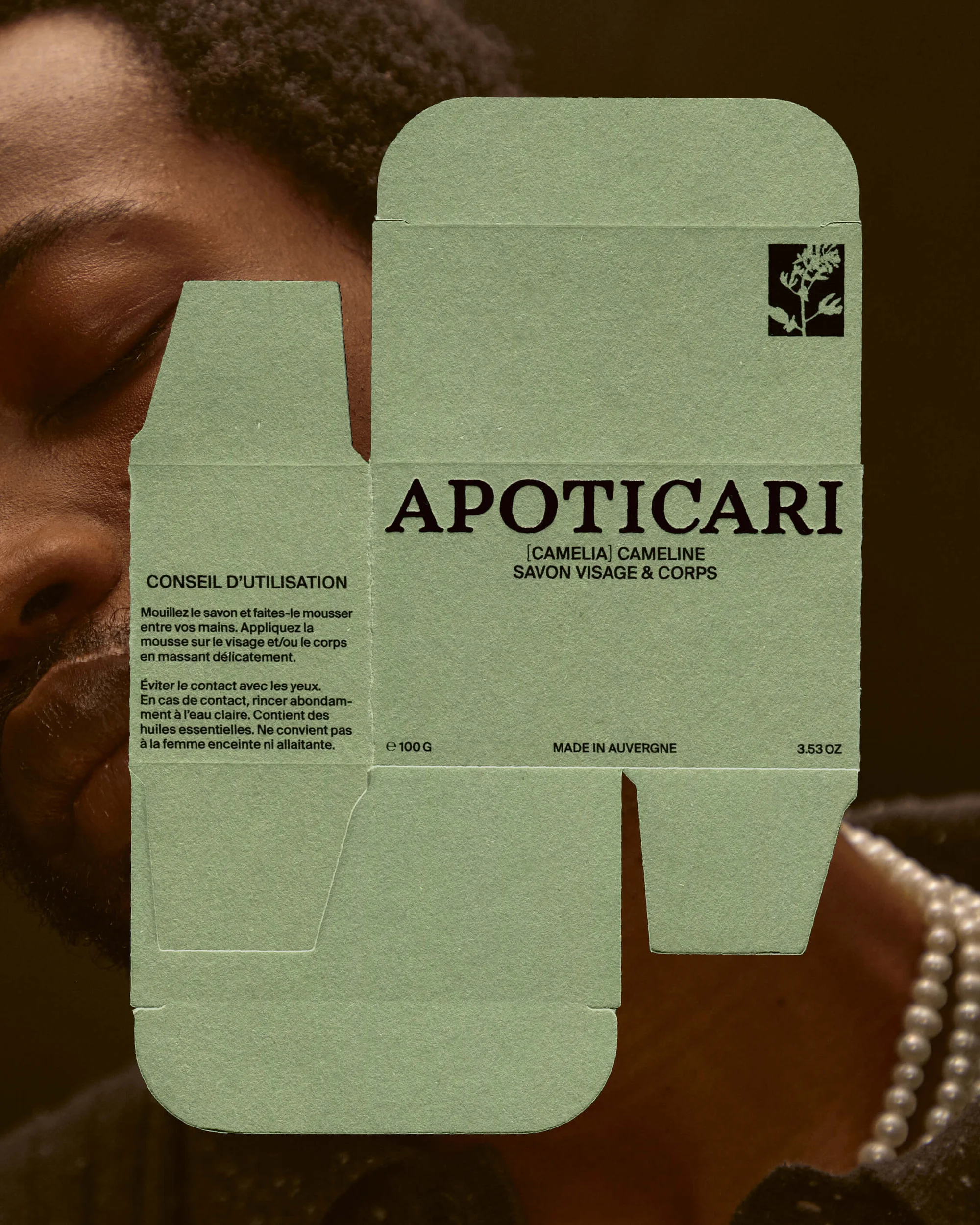 Soap packaging features bold 'APOTICARI' logo, facial product claim, and usage instructions, set against a backdrop of a partially visible person.
