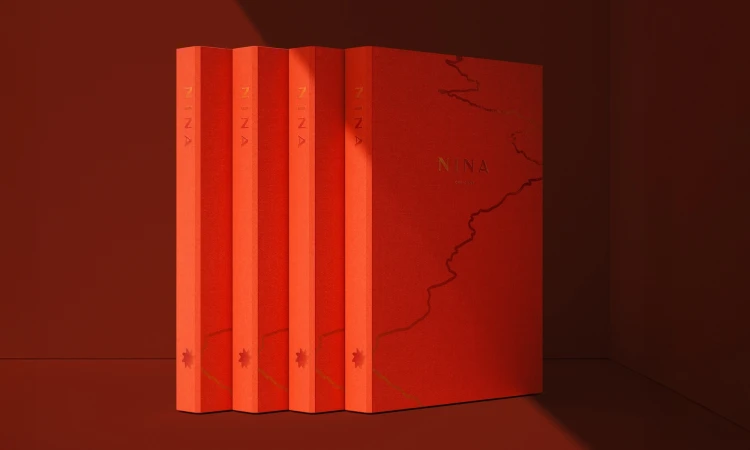 Four red hardcover books are stacked vertically, with the spine of each book visible, featuring the word "NINA" and a small graphic.
