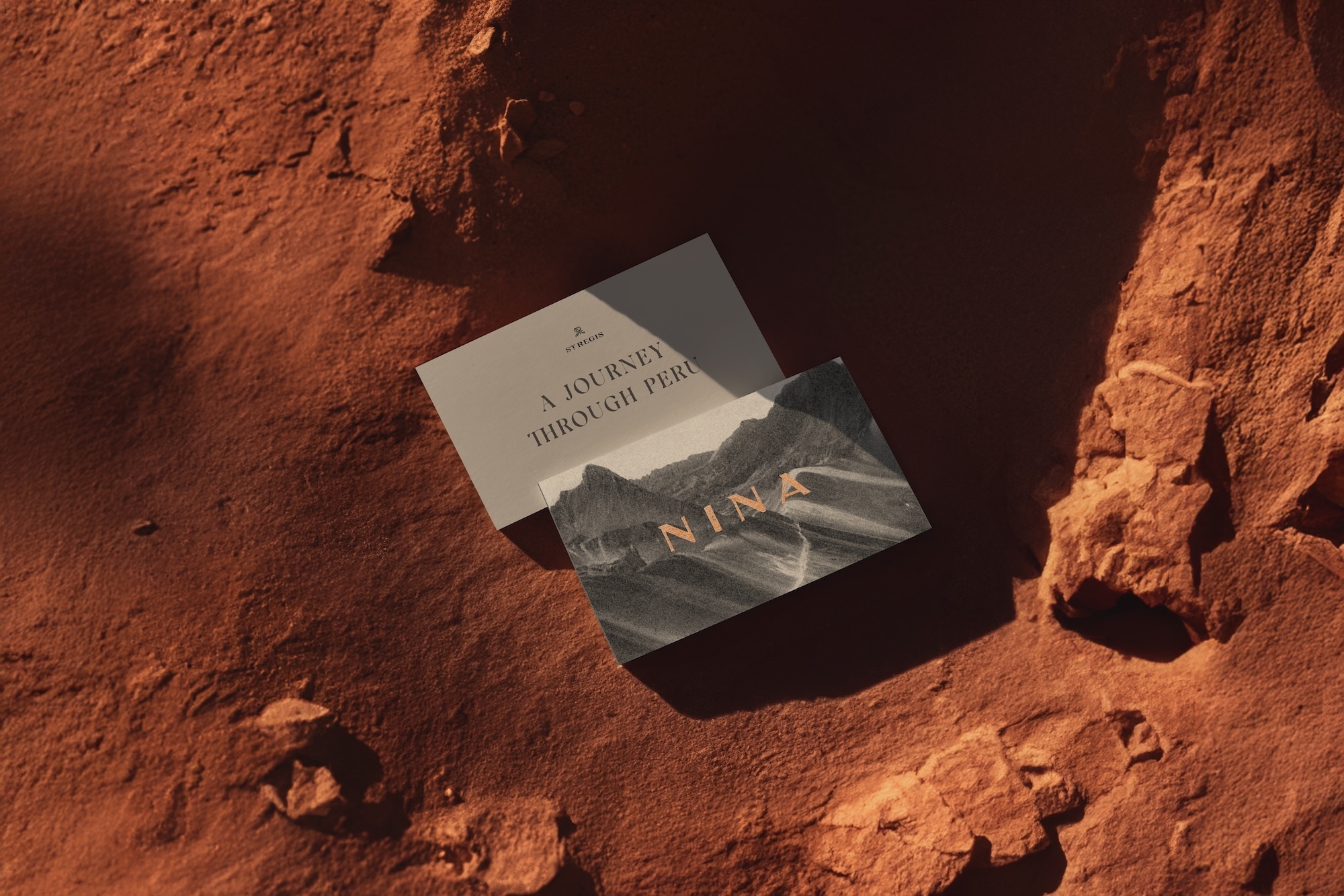 Business cards featuring a landscape graphic are displayed on a textured, sandy surface in warm lighting, showcasing travel industry imagery.