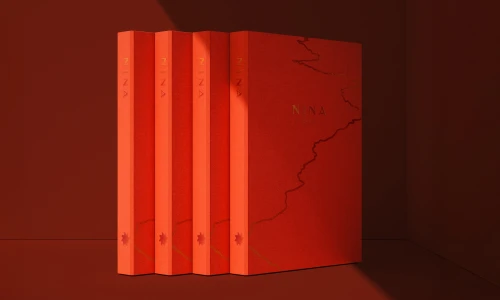 Four identical red books with gold foil typography and map details standing upright against a dark red backdrop.