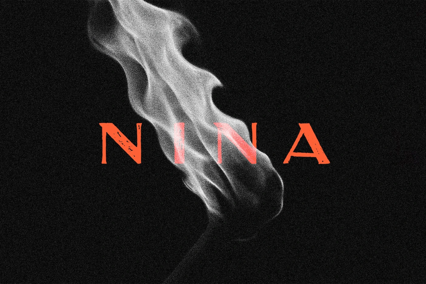 Close-up of a match flame glowing white against a dark textured background with the word NINA in red letters