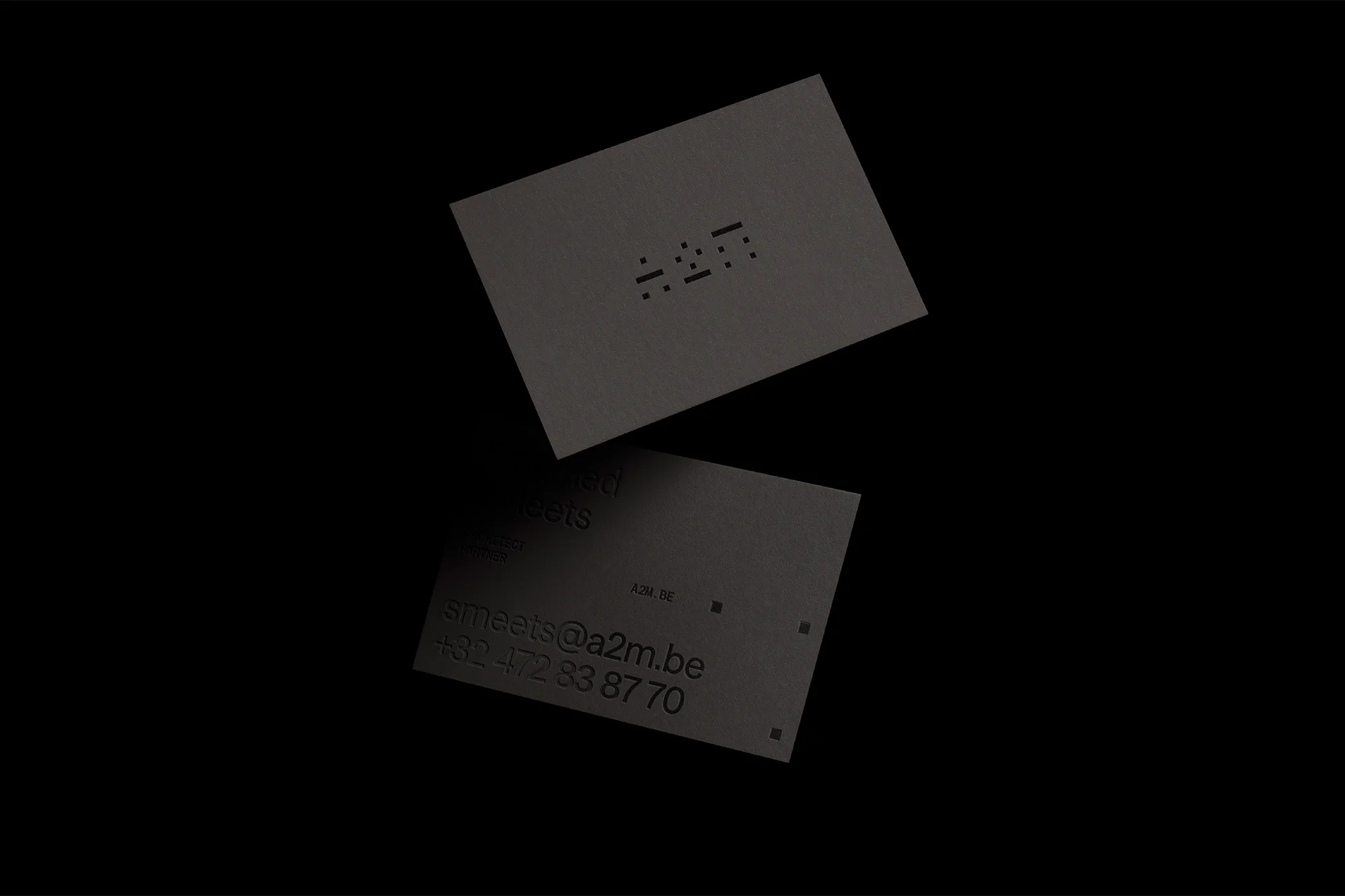 Two grey business cards, one floating and one at an angle, on a dark background with contact information and an icon visible.