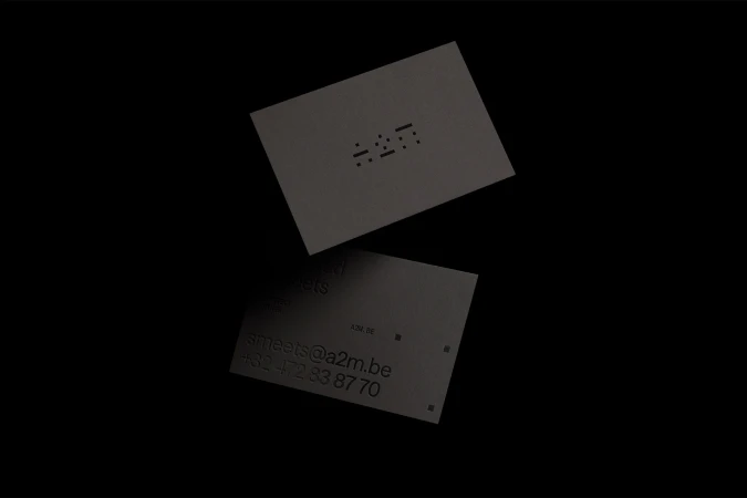 Two grey business cards, one floating and one at an angle, on a dark background with contact information and an icon visible.