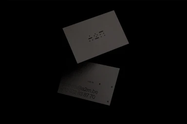 Two dark business cards with debossed minimalist typography and contact details on a black background.