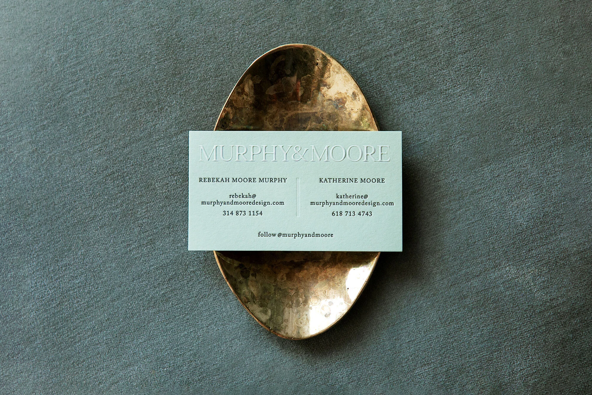 Mint green business card for Murphy & Moore Design on a decorative gold tray. The card features company name, contact info and follow info.