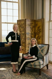 Two blonde women wearing matching black and white outfits in a classic living room interior for Murphy & Moore brand identity.