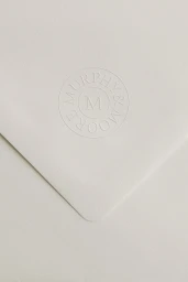 Embossed circular logo on heavy off-white paper envelope for Murphy and Moore brand identity.