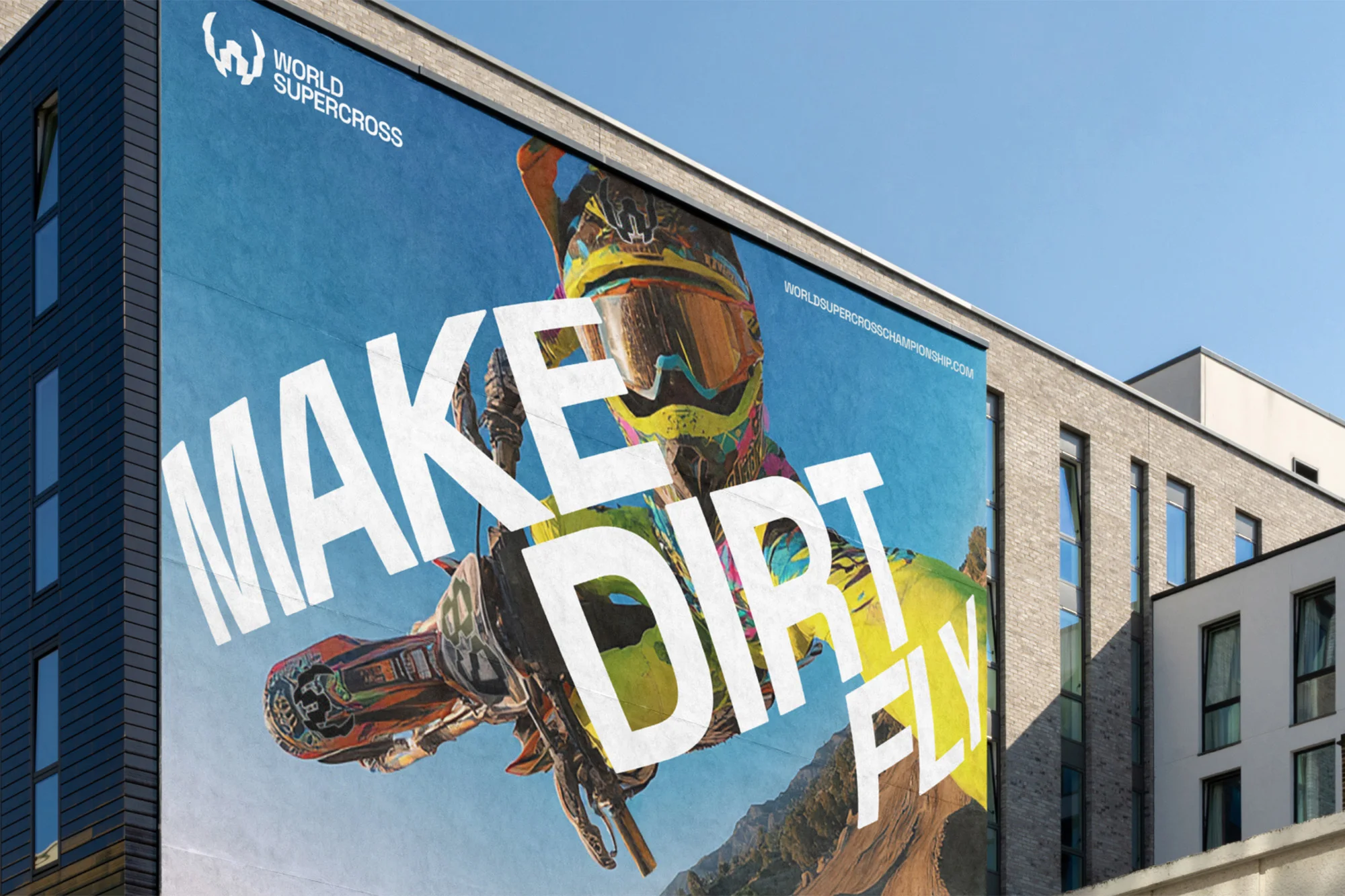 World Supercross Championship billboard featuring motocross rider jumping with 'Make Dirt Fly' text against a clear blue sky and building.
