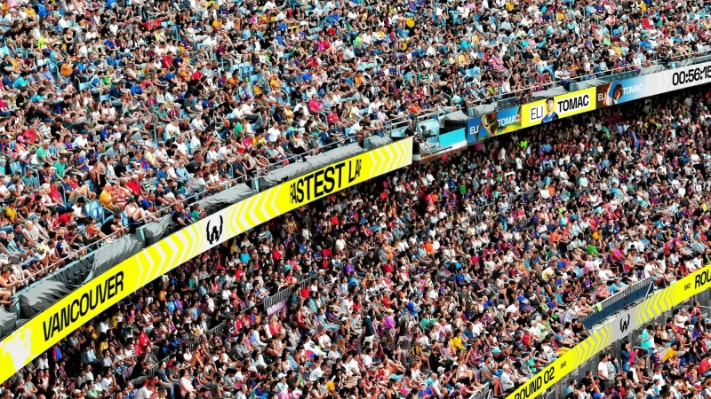 Large crowd of spectators fill stadium seating, creating a vibrant scene of anticipation and energy at the outdoor event.