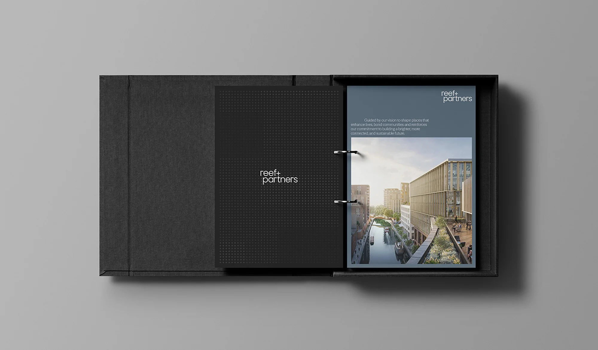 Open black presentation box featuring a binder displaying an architectural rendering of a modern building by a canal.