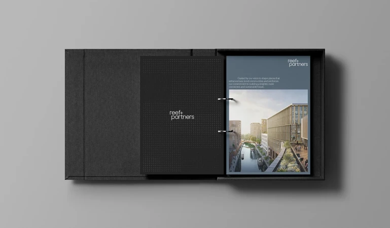 Open black presentation box featuring a binder displaying an architectural rendering of a modern building by a canal.