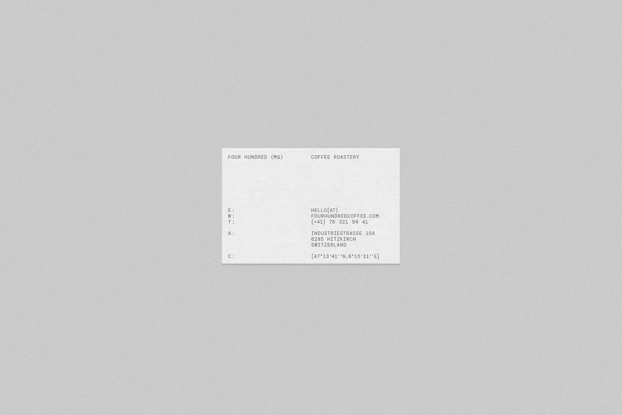Minimalist product shot of a business card with coffee roastery contact details against a neutral grey background, showcasing design.
