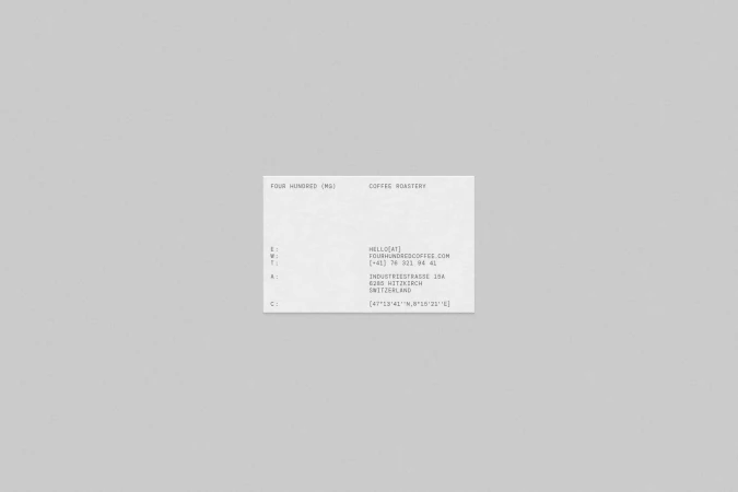 Minimalist product shot of a business card with coffee roastery contact details against a neutral grey background, showcasing design.