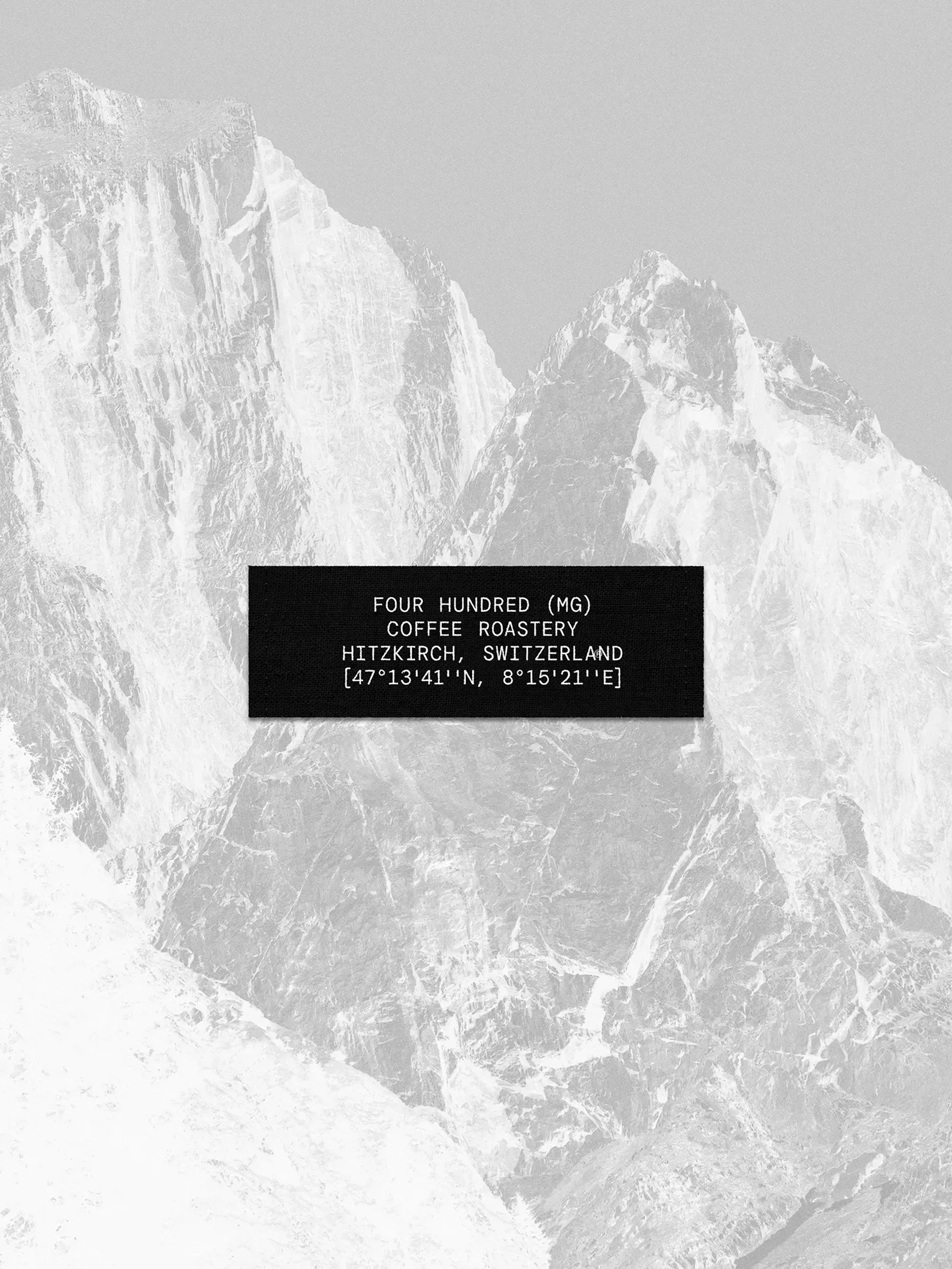 Monochromatic image of rocky mountains with a black rectangle in the foreground containing white text about a coffee roastery.