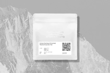 White coffee packaging bag with printed text and a QR code centered on a textured mountain background.