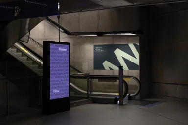 Branded transit display and illuminated pillar with typography in an underground transport station architecture