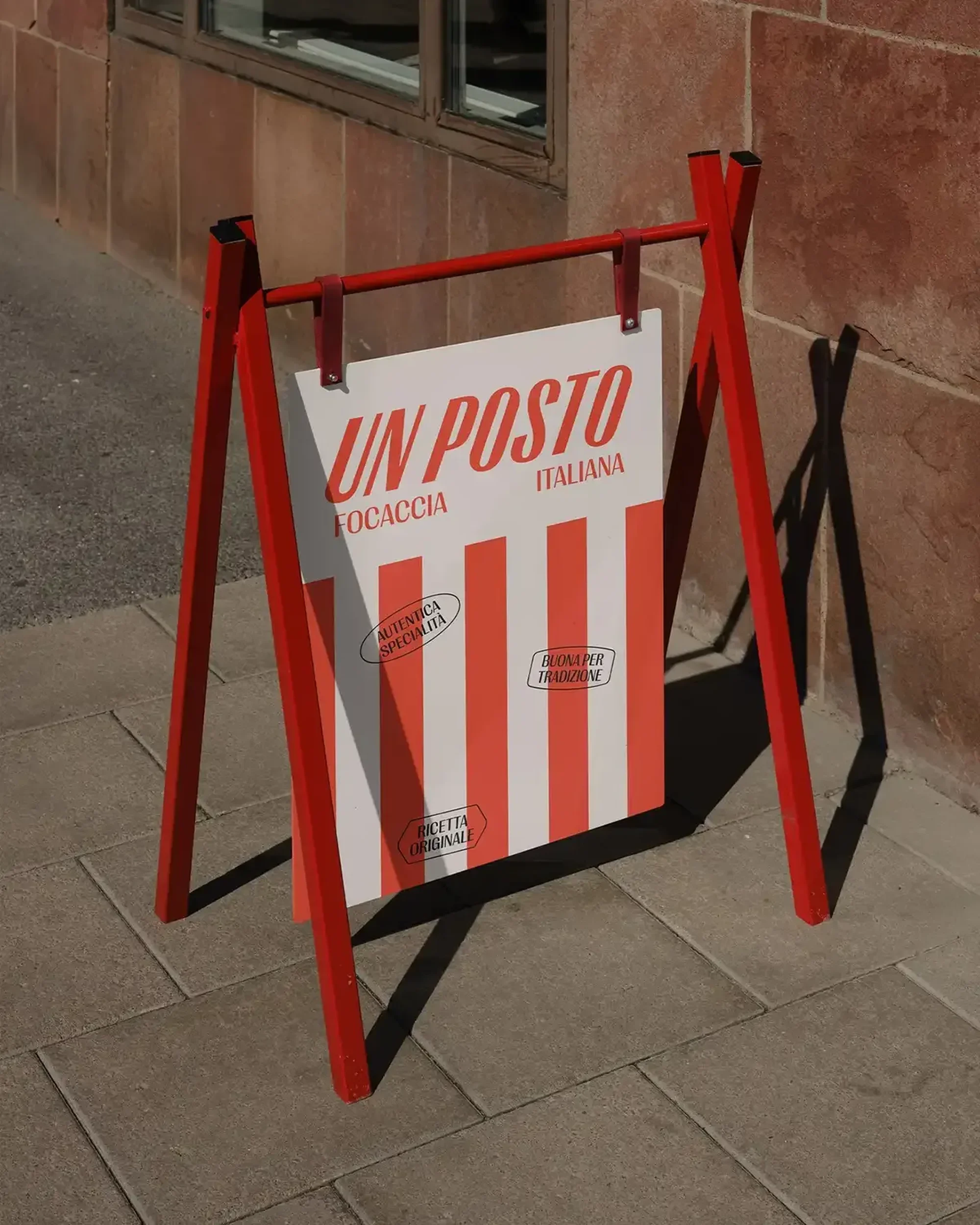 A red A-frame sandwich board sign advertises "Un Posto Focaccia Italiana" with red and white stripes, sitting on a paved surface.